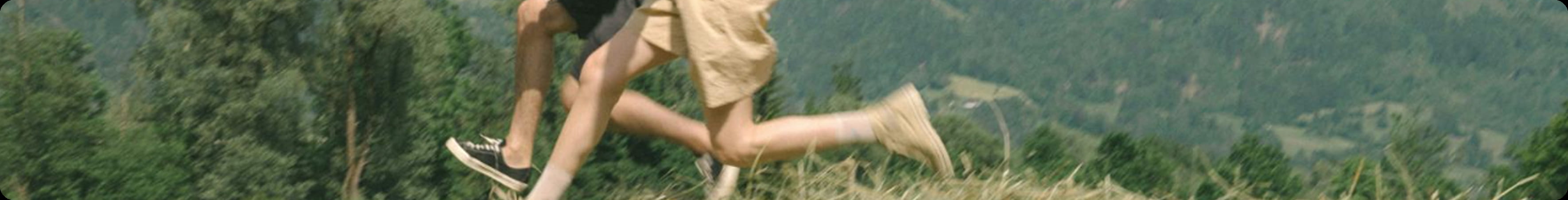 Two people jumping in grass